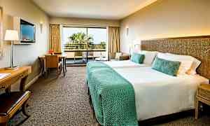 Hotelværelse med to senge og balkon. (AI-genereret tekst)