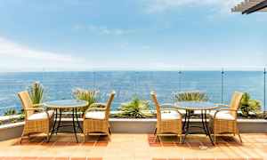 En terrasse med møbler i rattan og udsigt over havet. (AI-genereret tekst)