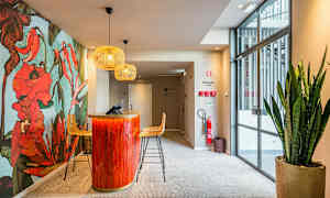 Reception med en dekorativ blomster væg, rød-orange reception og siddepladser med moderne lamper over. (AI-genereret tekst)