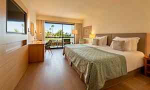 Moderne hotelværelse med dobbeltseng og altan i baggrunden. (AI-genereret tekst)