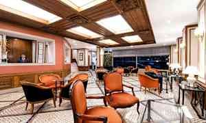 En elegant lounge med røde stole, marmorgulv og trædetaljer i loftet. (AI-genereret tekst)