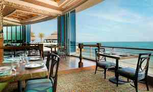 En restaurant med udsigt over havet, med glaspartier og elegante borddækninger. (AI-genereret tekst)