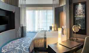 Hotelværelse med moderne indretning, seng og skrivebord. (AI-genereret tekst)