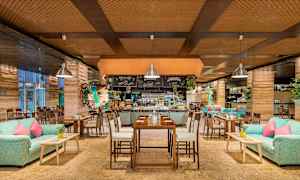 En restaurant med træinteriør, sofaer, borde og dekorationer. (AI-genereret tekst)