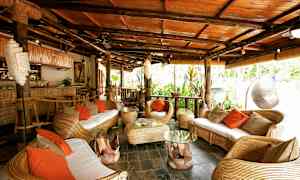 En tropisk indrettet siddegruppe med kurvemøbler og orange puder. (AI-genereret tekst)