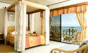 Et soveværelse med himmelseng og udsigt over havet fra en altan. (AI-genereret tekst)