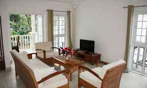 En lys stue med siddepladser til fire personer, et sofabord og et fjernsyn. (AI-genereret tekst)