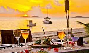 Middag ved et dækket bord ved solnedgang med havet i baggrunden. (AI-genereret tekst)