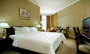 Et hotelværelse med en stor redt seng, lamper, spisebord og et fjernsyn. (AI-genereret tekst)