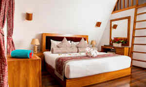 Et stilrent soveværelse med en dobbeltseng, trædetaljer og dekorerede puder. (AI-genereret tekst)