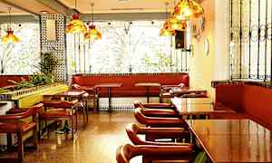 En restaurant med borde, stole og bænke ved vinduer med dekorative jerngitre. (AI-genereret tekst)