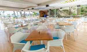 Udendørs restaurant med borde og stole foran panoramavinduer. (AI-genereret tekst)