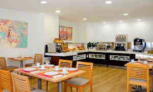 Spiseområde med dækkede borde og buffet med kaffemaskine og morgenmadsvalg. (AI-genereret tekst)