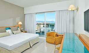 Et hotelværelse med en dobbeltseng, en lænestol og et glasbord. (AI-genereret tekst)