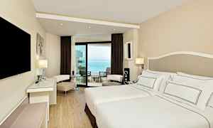 Et moderne hotelværelse med en dobbeltseng og en balkon med havudsigt. (AI-genereret tekst)