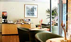 En kaffestation og siddeområde på et hotel eller café. En kaffemaskine og snacks er placeret på et skab. (AI-genereret tekst)