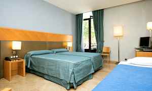 Hotelværelse med to senge, gardiner og vindue. (AI-genereret tekst)