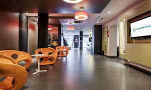 En moderne hotellobby med orange stole og små hvide borde. (AI-genereret tekst)