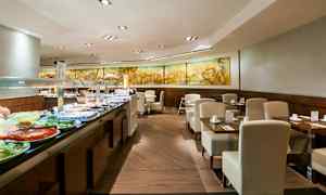 Billedet viser en buffetrestaurant med moderne møbler og et udvalg af mad anrettet på en buffetskranke. (AI-genereret tekst)