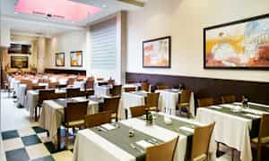 Spisesal med dækkede borde og ophængte malerier på væggene. (AI-genereret tekst)