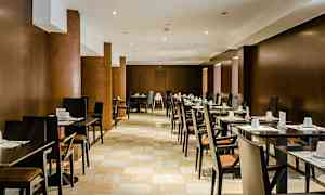 Et restaurantområde med rækker af borde og stole, dækket til gæster. (AI-genereret tekst)