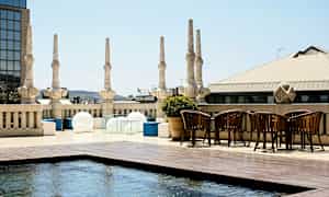 En tagterrasse med søjler, moderne møbler og et lavt vandbassin. (AI-genereret tekst)