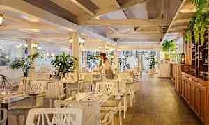 Interiør af en restaurant med træelementer, hvide møbler og grønne planter. (AI-genereret tekst)