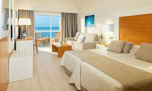 Et hotelværelse med dobbeltseng, siddeområde og altan med havudsigt. (AI-genereret tekst)