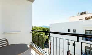 Altan med bord og stole, udsigt til grønt område og nærliggende bygninger. (AI-genereret tekst)