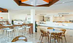 En moderne restaurant med hvide borde og stole. En buffetsektion ses i baggrunden. (AI-genereret tekst)