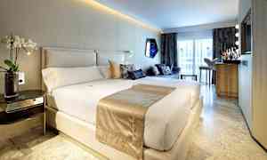 Et moderne hotelværelse med en stor seng, sofagruppe og en minibar foran et stort vindue. (AI-genereret tekst)