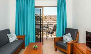 Stue med mørke møbler, blå gardiner og udsigt fra altan. (AI-genereret tekst)