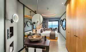 Interiør af et elegant hotelværelse med seng, badeværelse og havudsigt. (AI-genereret tekst)