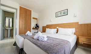 Dobbeltværelse med en seng, trædetaljer og hvide vægge. (AI-genereret tekst)