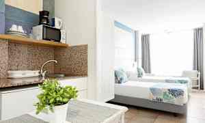 Interiør af et hotelværelse med et tekøkken og to enkeltsenge. (AI-genereret tekst)