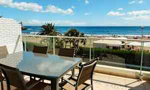 En møbelgruppe på en altan med udsigt til stranden og havet. (AI-genereret tekst)