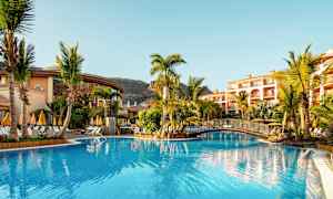 Poolområde med parasoller og palmer ved et hotel. (AI-genereret tekst)