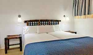 Et soveværelse med en dobbeltseng, blå-rutede sengeryg og hvidt sengetøj. (AI-genereret tekst)