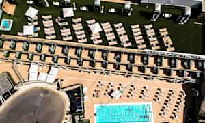 Luftfoto af hotelområde med pool, liggestole og parasoller. (AI-genereret tekst)