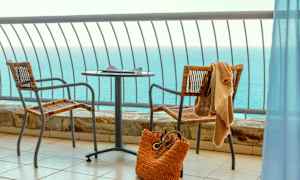 Udsigt over havet fra en altan med bord, to stole og en strandtaske. (AI-genereret tekst)