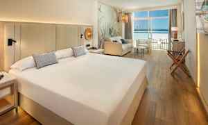 Hotelværelse med stor seng, siddegruppe og balkon med havudsigt. (AI-genereret tekst)