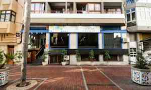 Indgangen til et lejlighedshotel med potteplanter udenfor. (AI-genereret tekst)