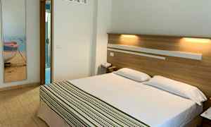 Hotelværelse med en dobbeltseng og badeværelsesdør i baggrunden. (AI-genereret tekst)