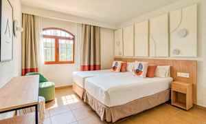 Et lyst og moderne indrettet hotelværelse med to enkeltsenge, en vinduesudsigt og dekorative elementer. (AI-genereret tekst)