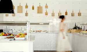 Billede af et buffetområde med frugt og salat, en person går forbi. (AI-genereret tekst)