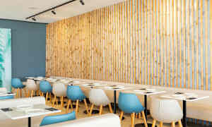 Restaurant med lyse borde og moderne stole foran en træpanel. (AI-genereret tekst)