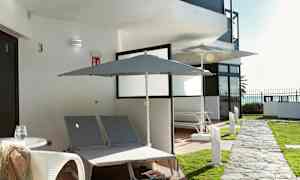 Udendørsområde med to liggestole og parasoller ved en bygning. (AI-genereret tekst)