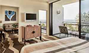 Hotelværelse med seng, møbler og altan med havudsigt. (AI-genereret tekst)