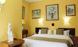 Et hotelværelse med en dobbeltseng, dekorerede vægge med malerier og en lille statue på et møbel. (AI-genereret tekst)