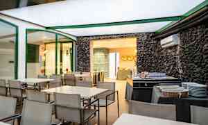 Spiseområde med borde og stole samt en buffetopsætning ved siden af en stenmur. (AI-genereret tekst)